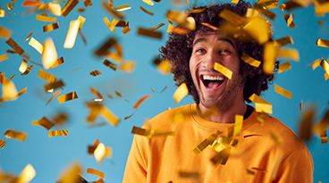 Celebrating Young Man With Mobile Phone Winning Prize And Showered With Gold Confetti In Studio