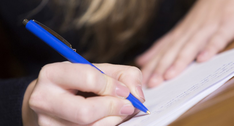 Student writing on exam sheet