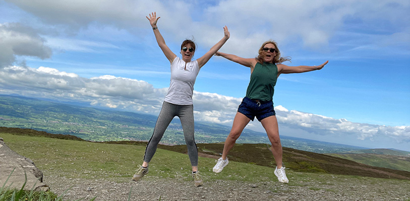 Two women in sportswear jumping for joy in the countryside