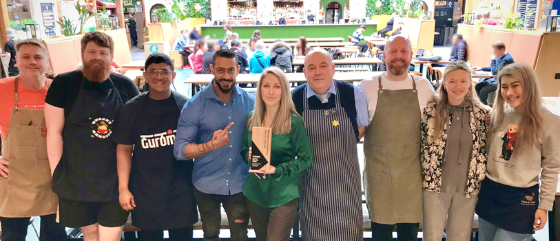 Chester Market wins Taste of Cheshire Award. Group of people stood in the market. 