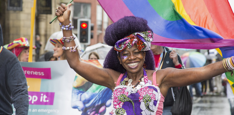 A woman walking in the Chester Pride parade waving a rainbow flag.
