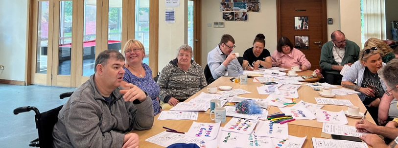 Group of people sat round a table at a workshop. 