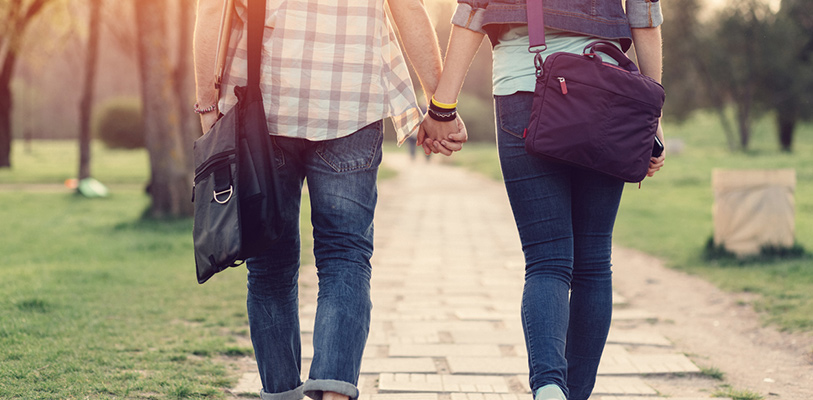 Young couple holding hands and walking outside.