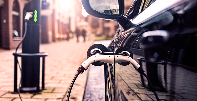 Electric vehicle charging station in street with black car