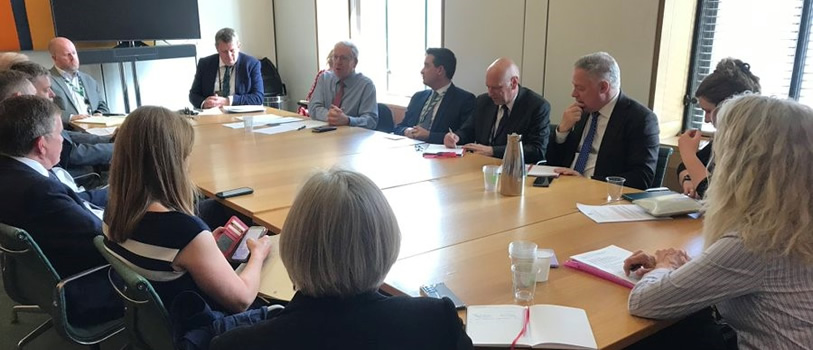 A group of people sat around a table having a meeting. 