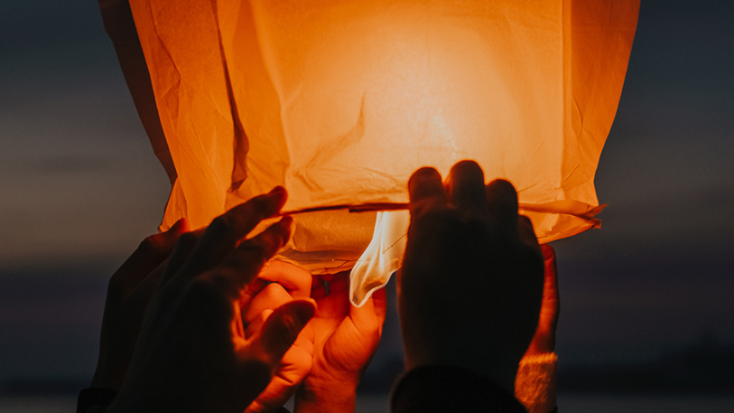 Hands about to release burning sky lantern