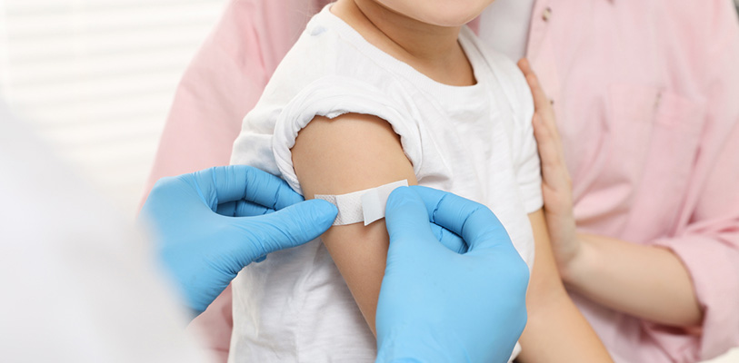 Mother with her daughter in clinic. Doctor sticking medical plaster on little girl's arm.
