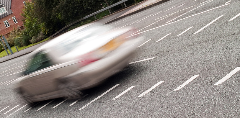 Car passing speed camera markings on an urban road.