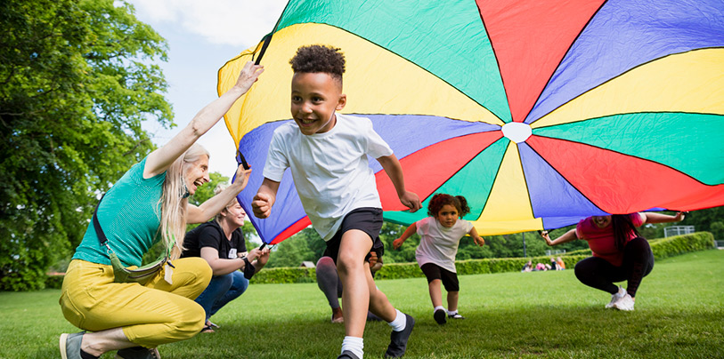 A child running underneath a colourful parachute