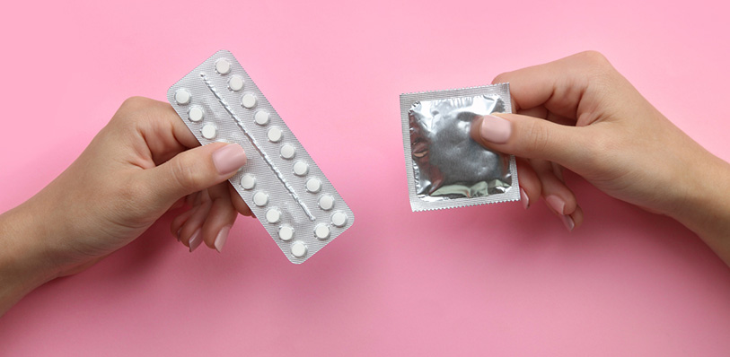 Person holding contraceptive pills and condom
