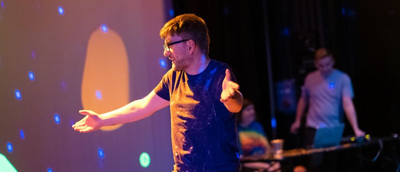 A person dancing with a DJ in the background.