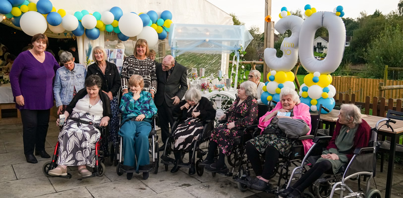 Staff who have worked in supported living since the start, along with residents of 30 years, enjoy a group photo.