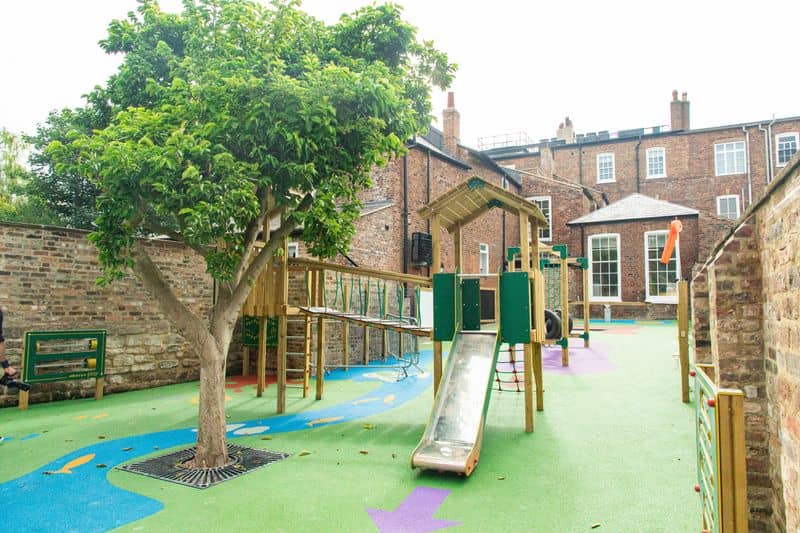 Climbing frame and slide next to tree in playground