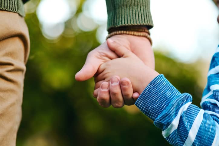 Parent holding child's hand.
