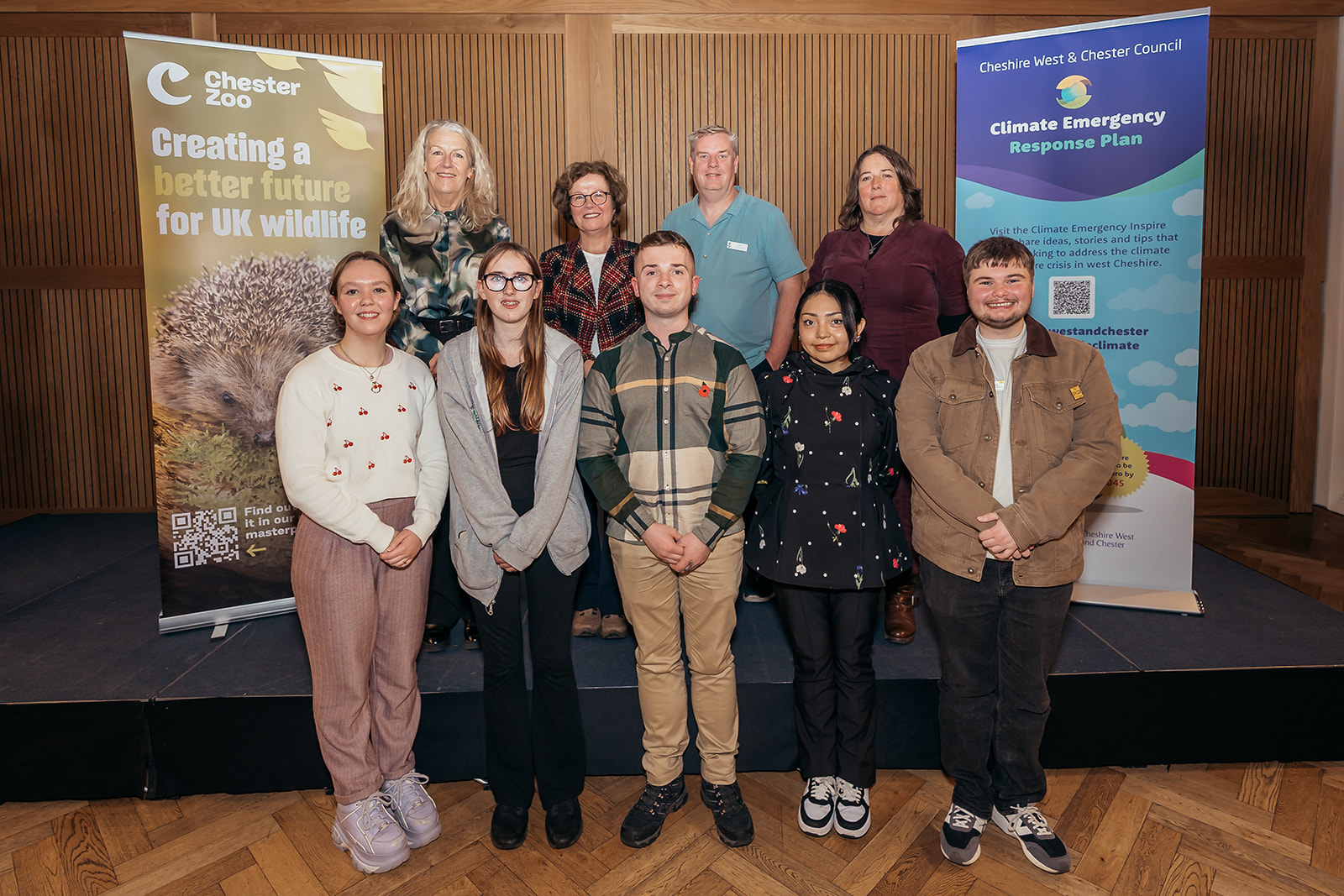 Speakers and panel members from the West Cheshire Action on Climate and Nature event standing by two banners
