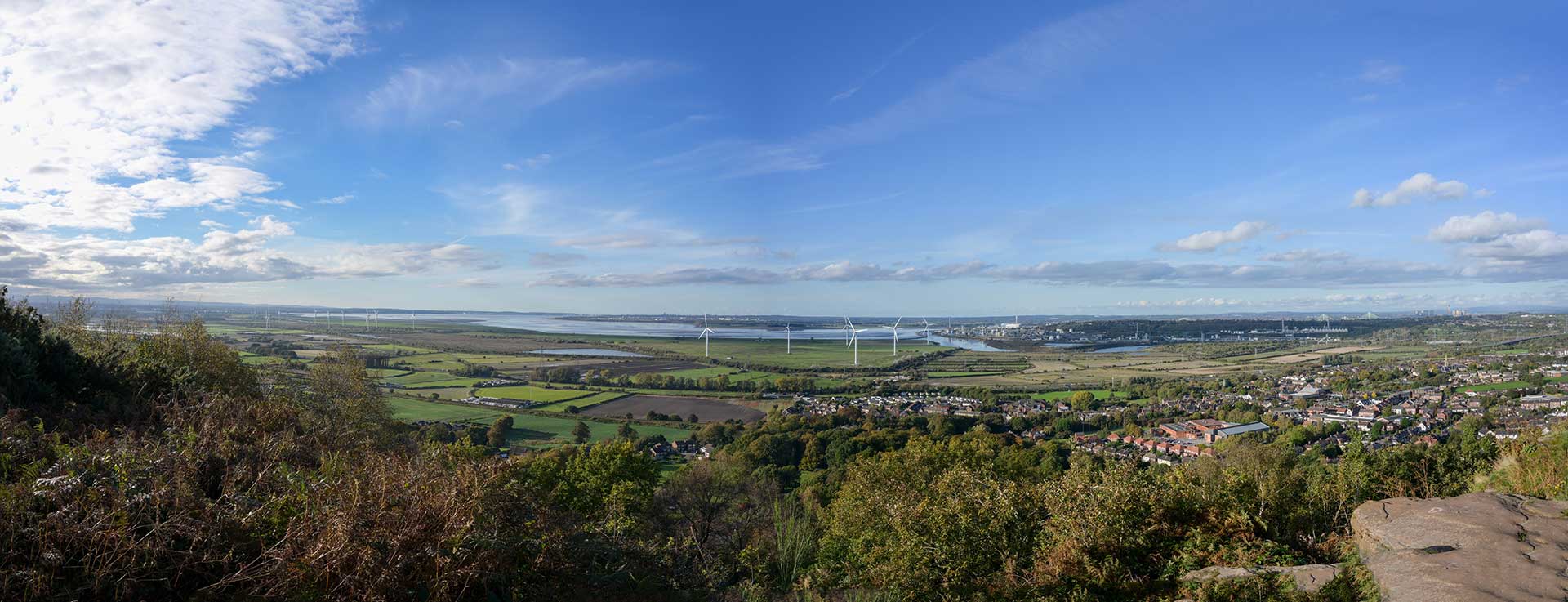 Panoramic shot of landscape including wind farms, countryside and blue sky