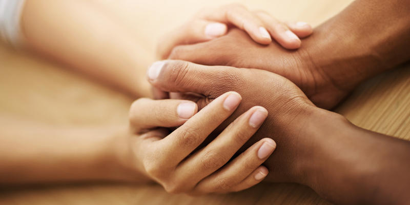 Two sets of hands holding each other supportively.