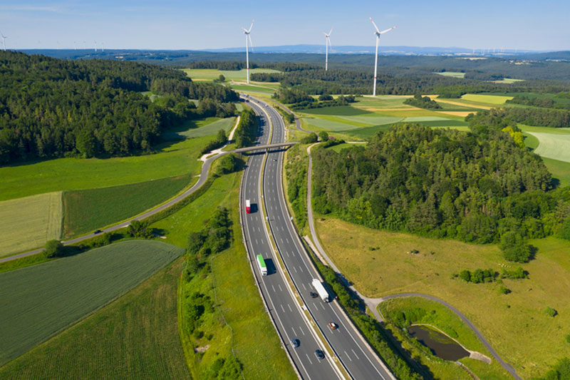 Trucks and wind turbines on highway.