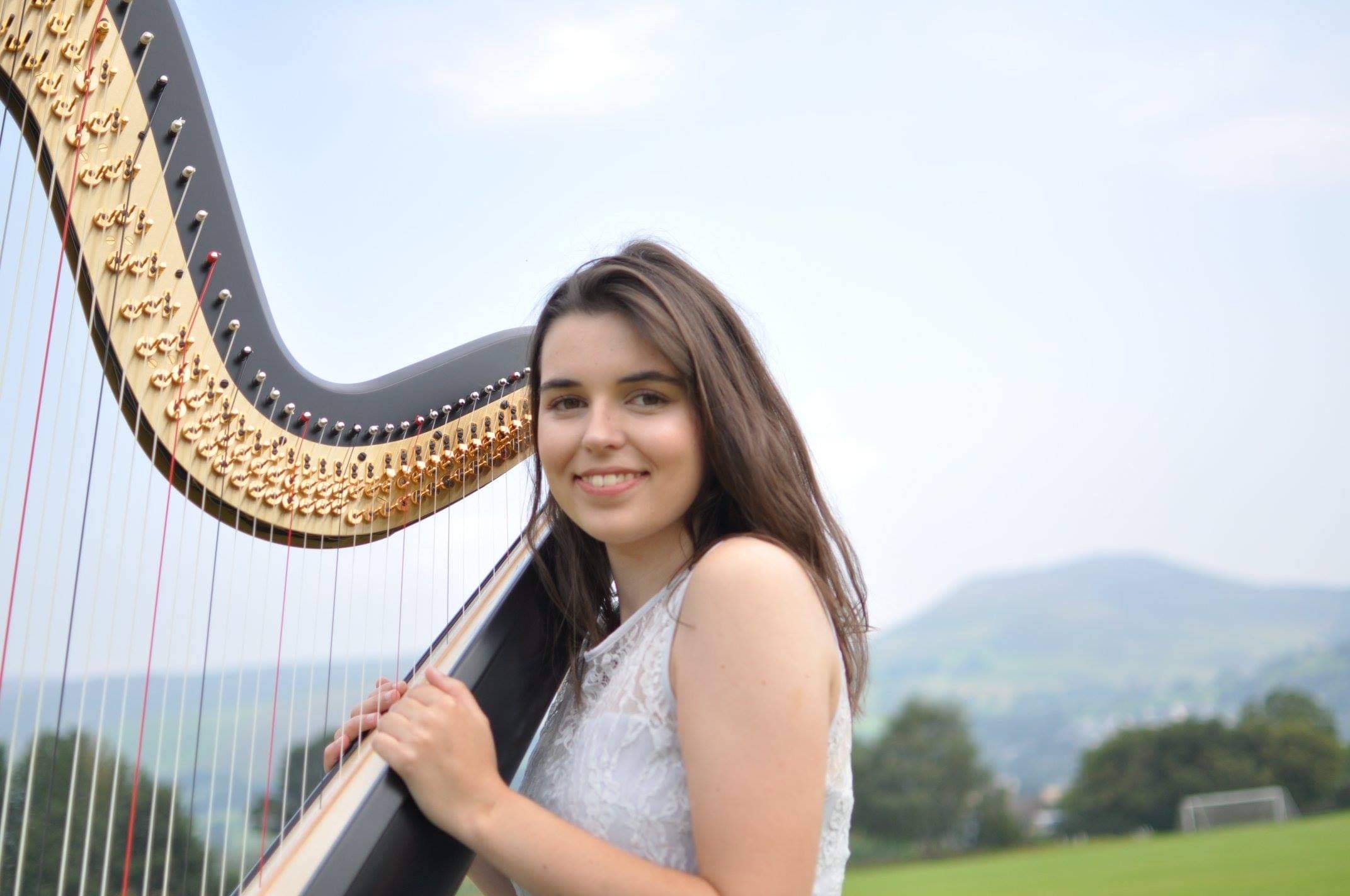 Young woman holding harp outdoors