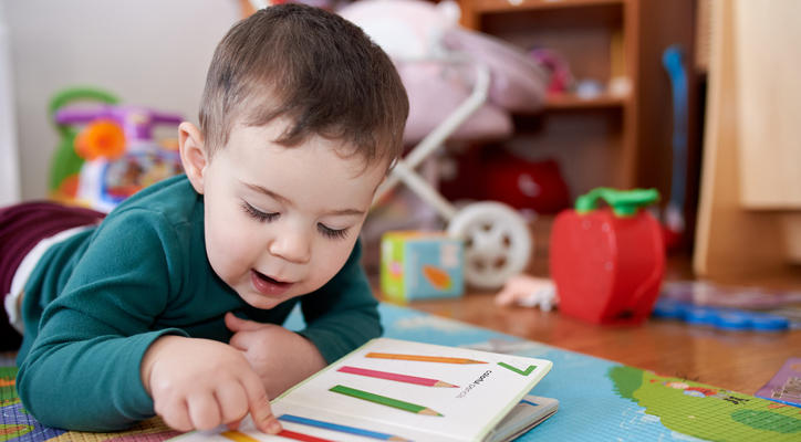 Young child on a playmat with a book