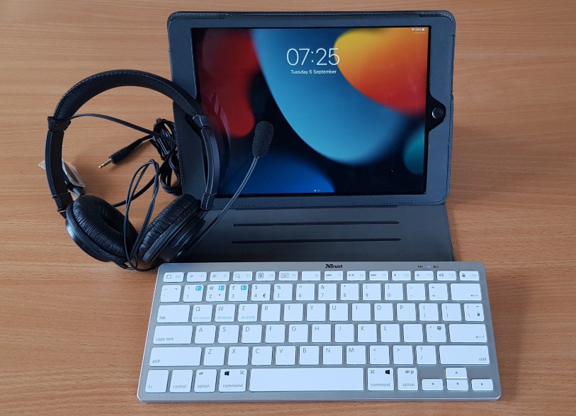 An iPad with a bluetooth keyboard and plug in headphones. 