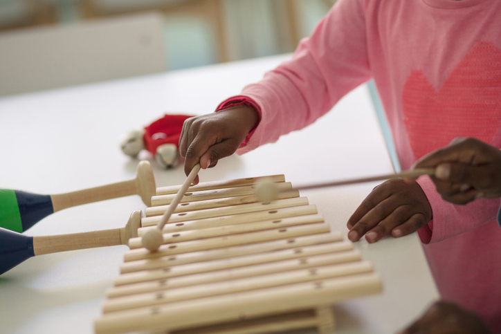 a child's hands playing a xylophone