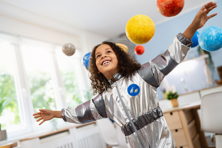 Child astronaut surrounded by planets