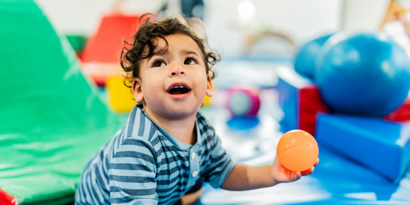 A young child crawling on a padded play mat