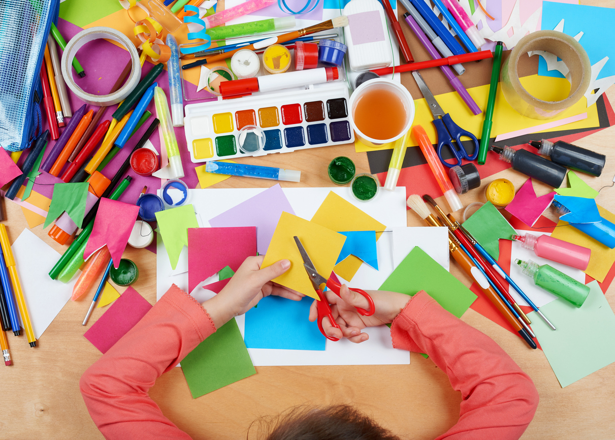 Craft materials with a child cutting paper