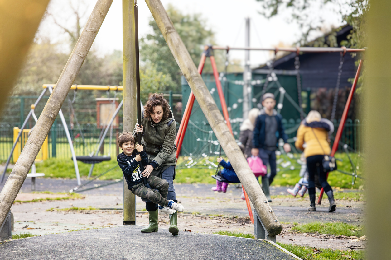 Mum and son playing on a zipwire in a park
