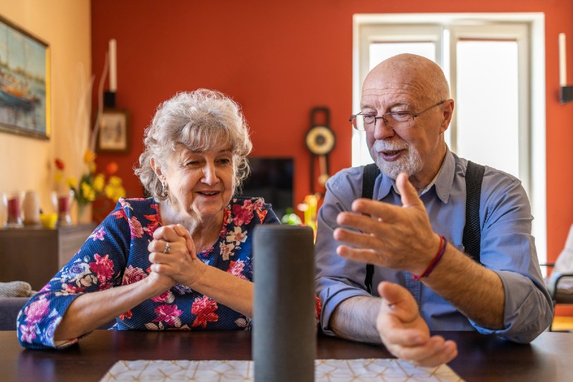 Older woman and man looking at Alexa.