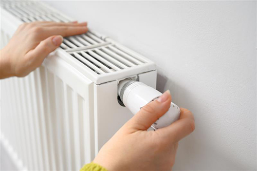 Person's hand adjusting a radiator dial