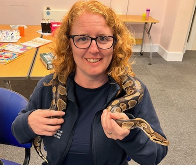 Woman wearing glasses smile, with a snake around her neck.