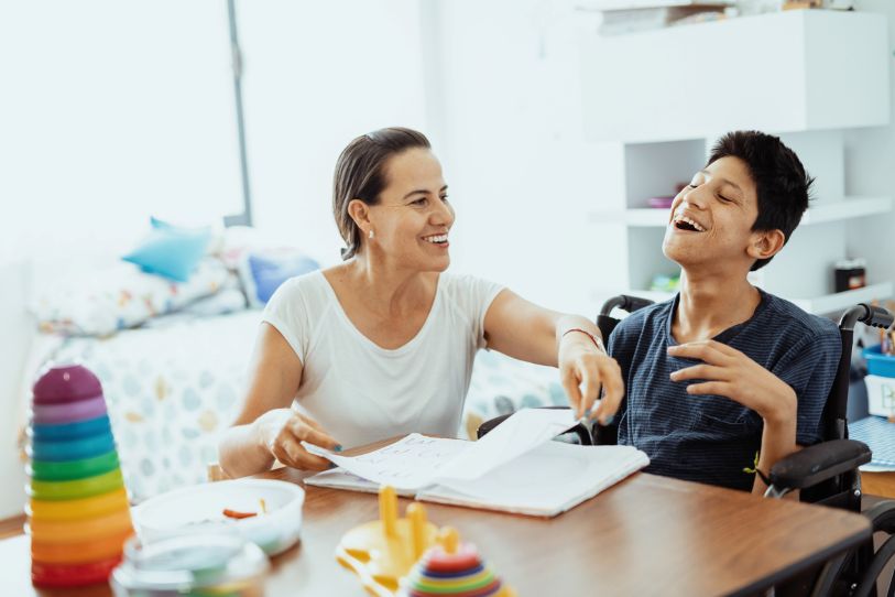 A childcare worker helps a smiling boy with his work. 