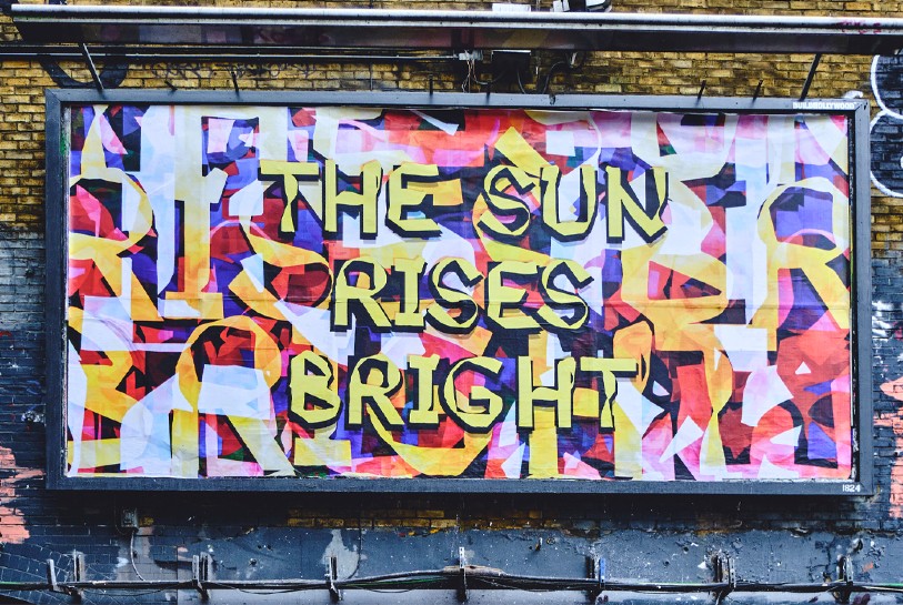 An example of artist Mark Titchner's work: a colourful billboard spelling 'The sun rises bright'