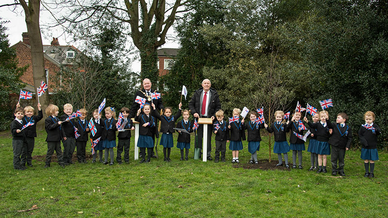 Pupils holding England flags and stood with Councillors.