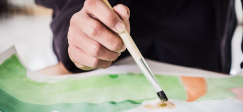 A hand holding a paintbrush painting a picture