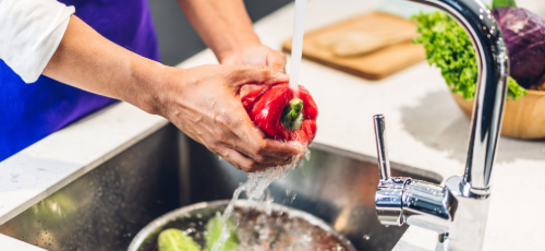 A man washing a red pepper under a tap