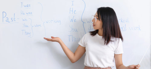 A woman at a whiteboard teaching English