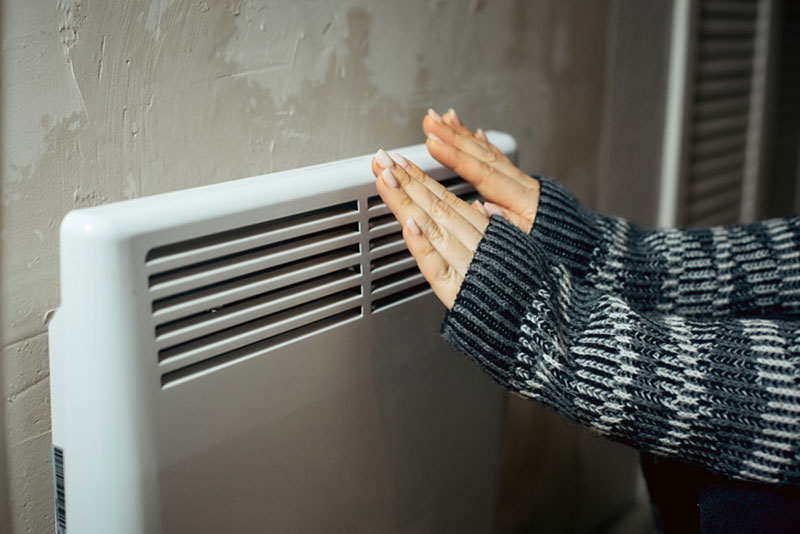 Woman warming hands on radiator